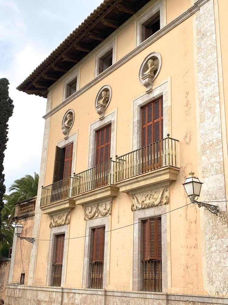 Fassade eines historischen Palacio in einem mallorquinischen Ort mit Büsten, Steinmetzarbeiten und hölzernen Fensterläden